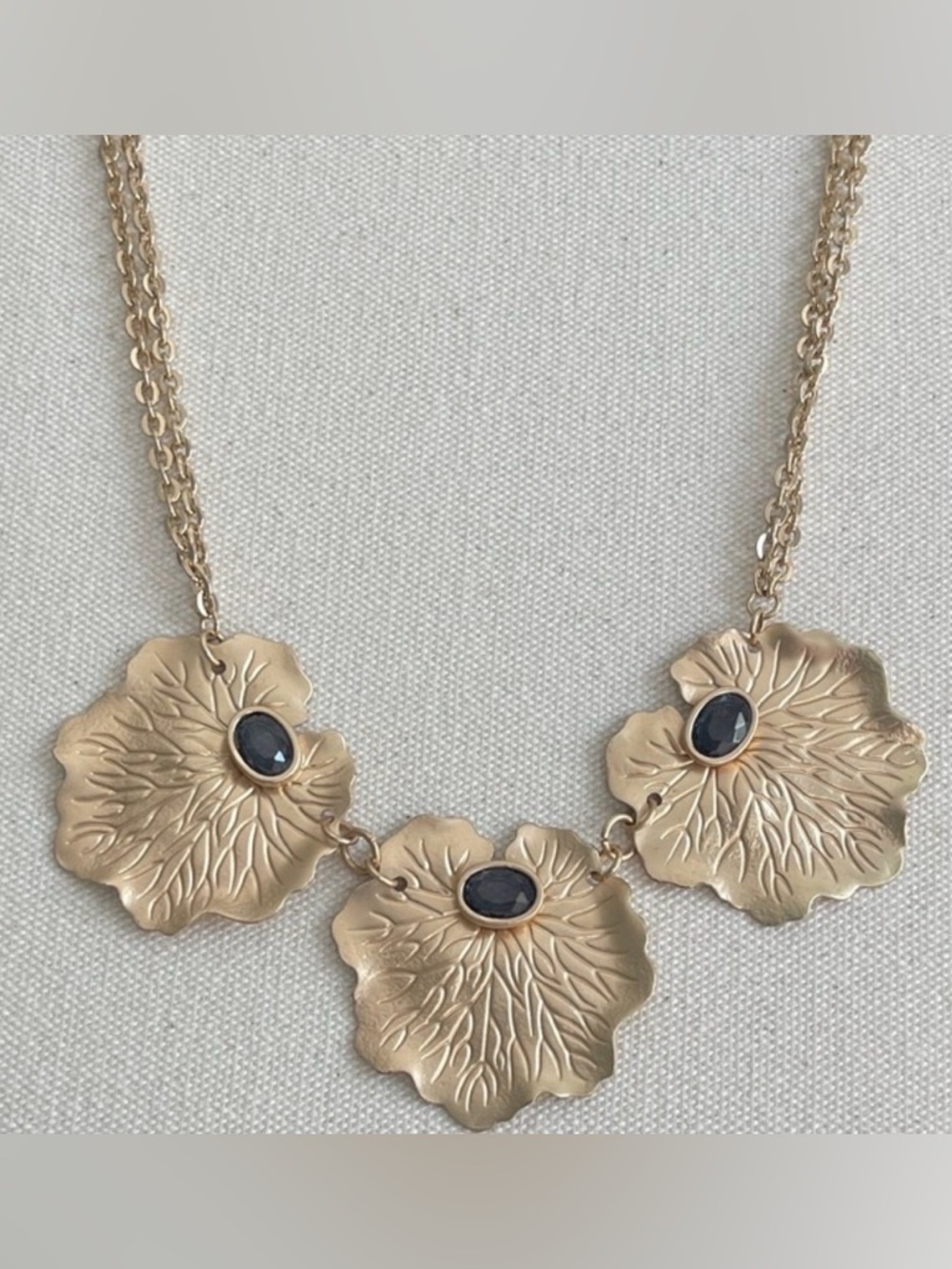 Elegant gold-tone floral necklace featuring three textured pendant Black Stone